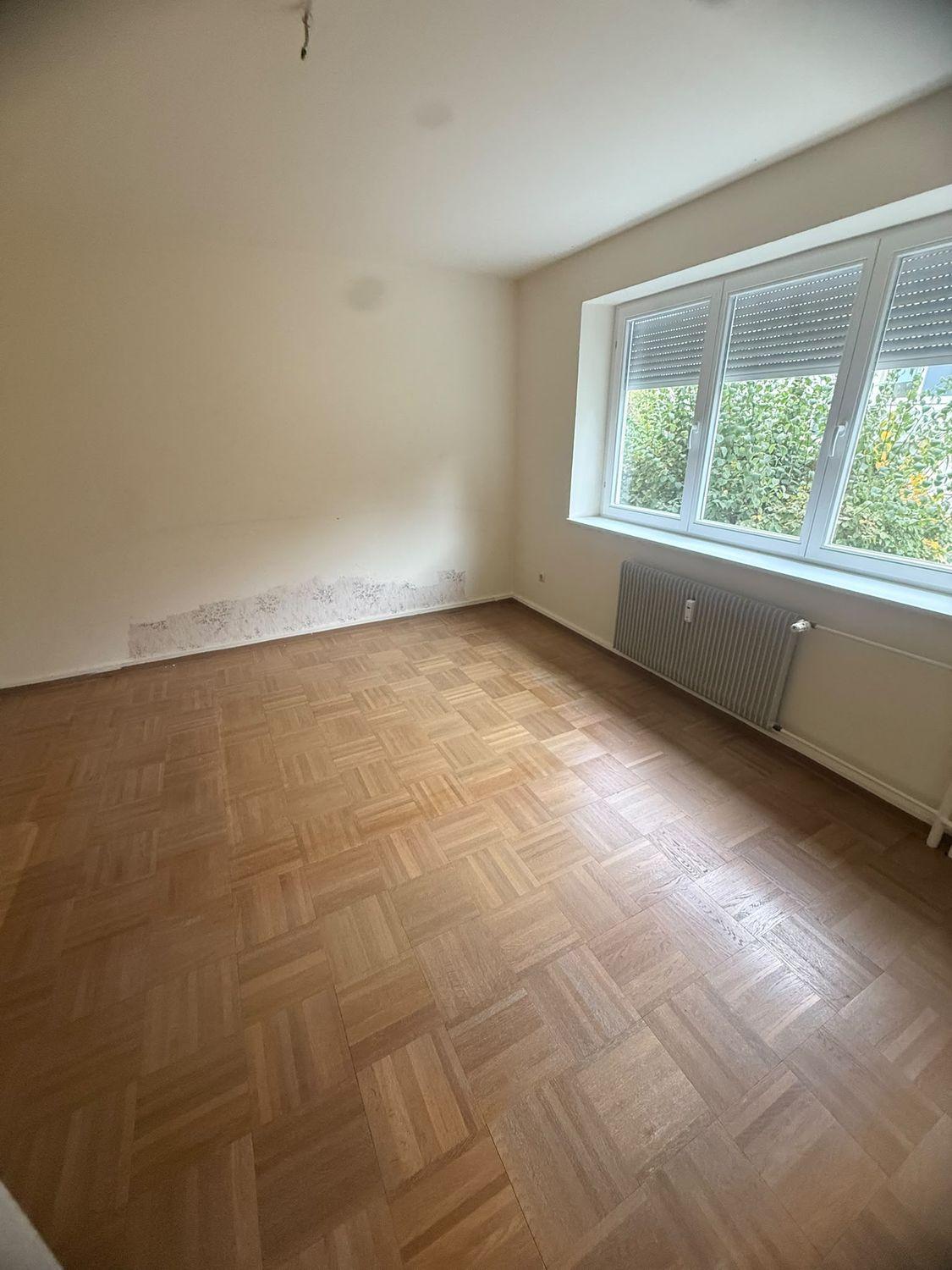 Leer geräumtes Zimmer mit Parkett und breitem Fenster