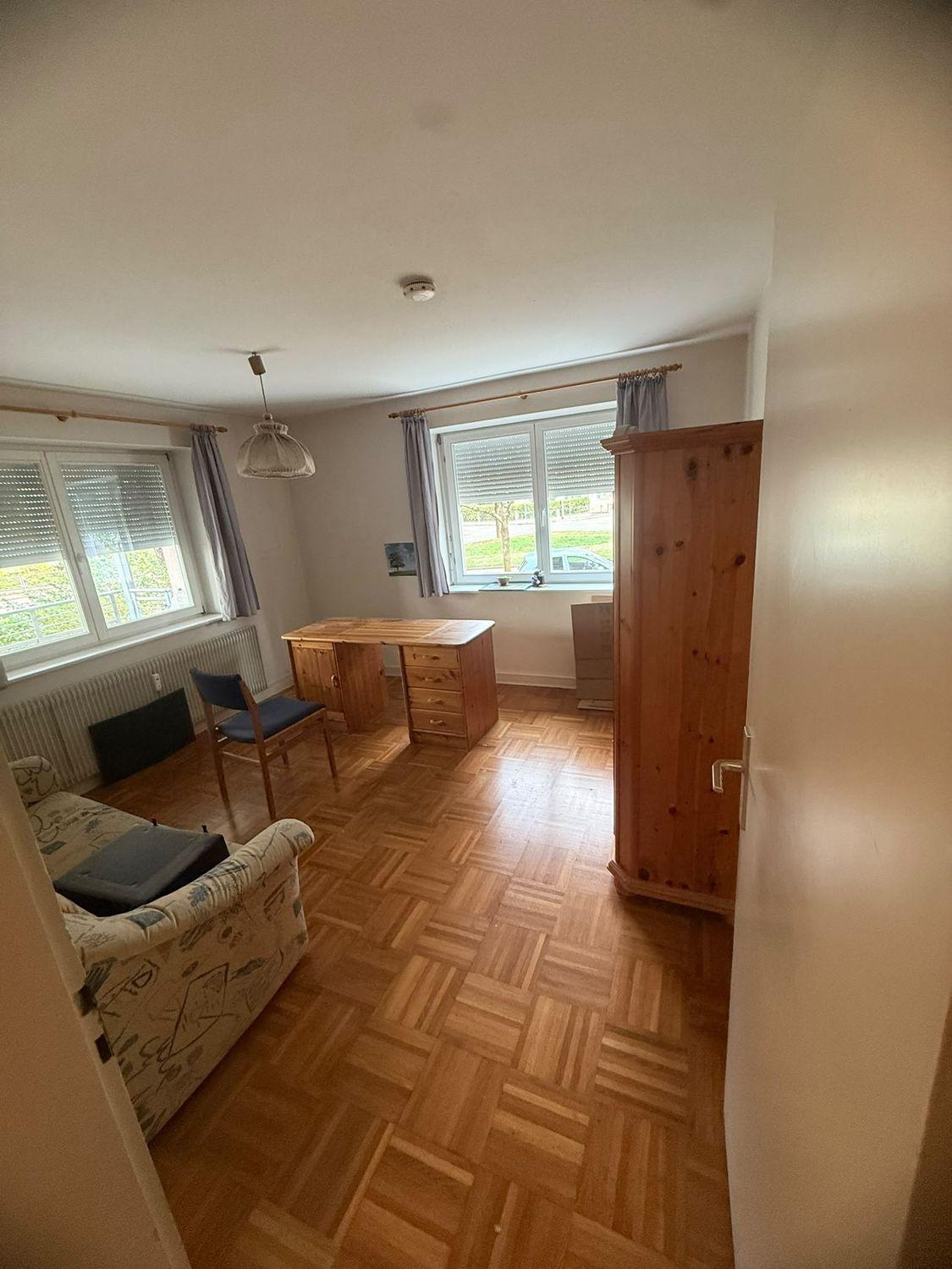 Zimmer mit Schreibtisch, Kleiderschrank und Sofa vor der Räumung